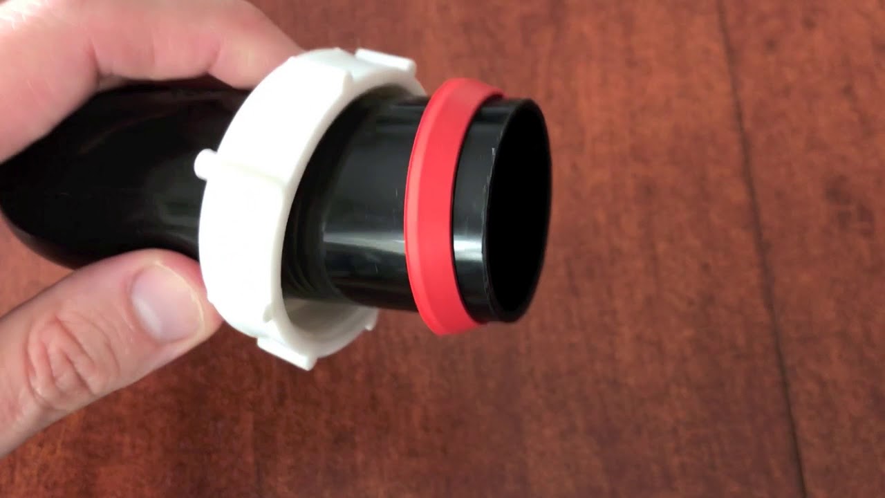 A PVC P-trap under a sink while a hand uses tongue-and-groove pliers to gently snug a slip nut
