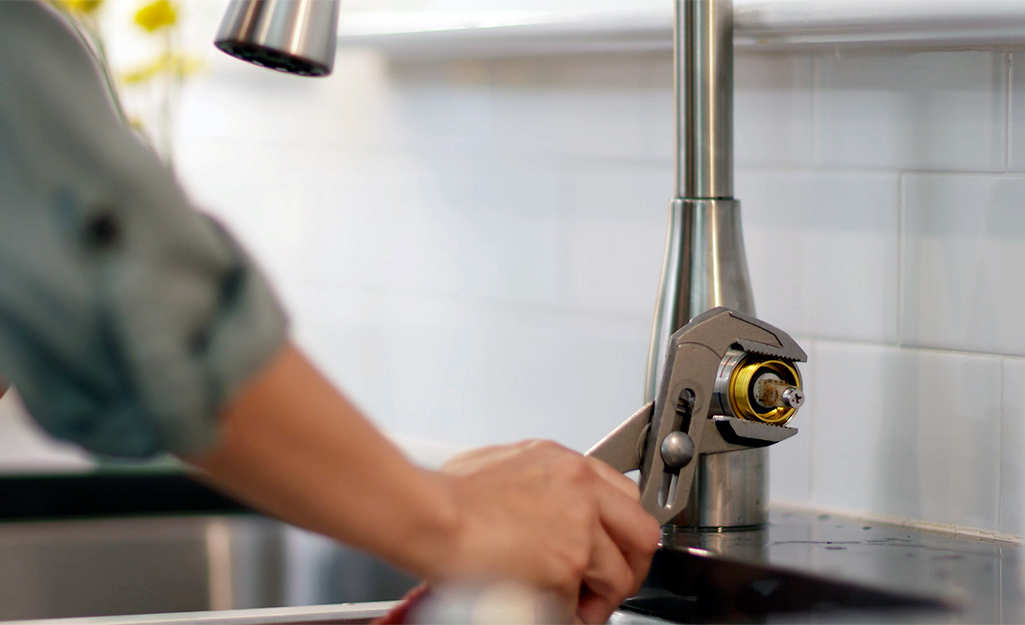A close-up of a single-handle faucet with the handle removed, exposing the cartridge and retaining nut