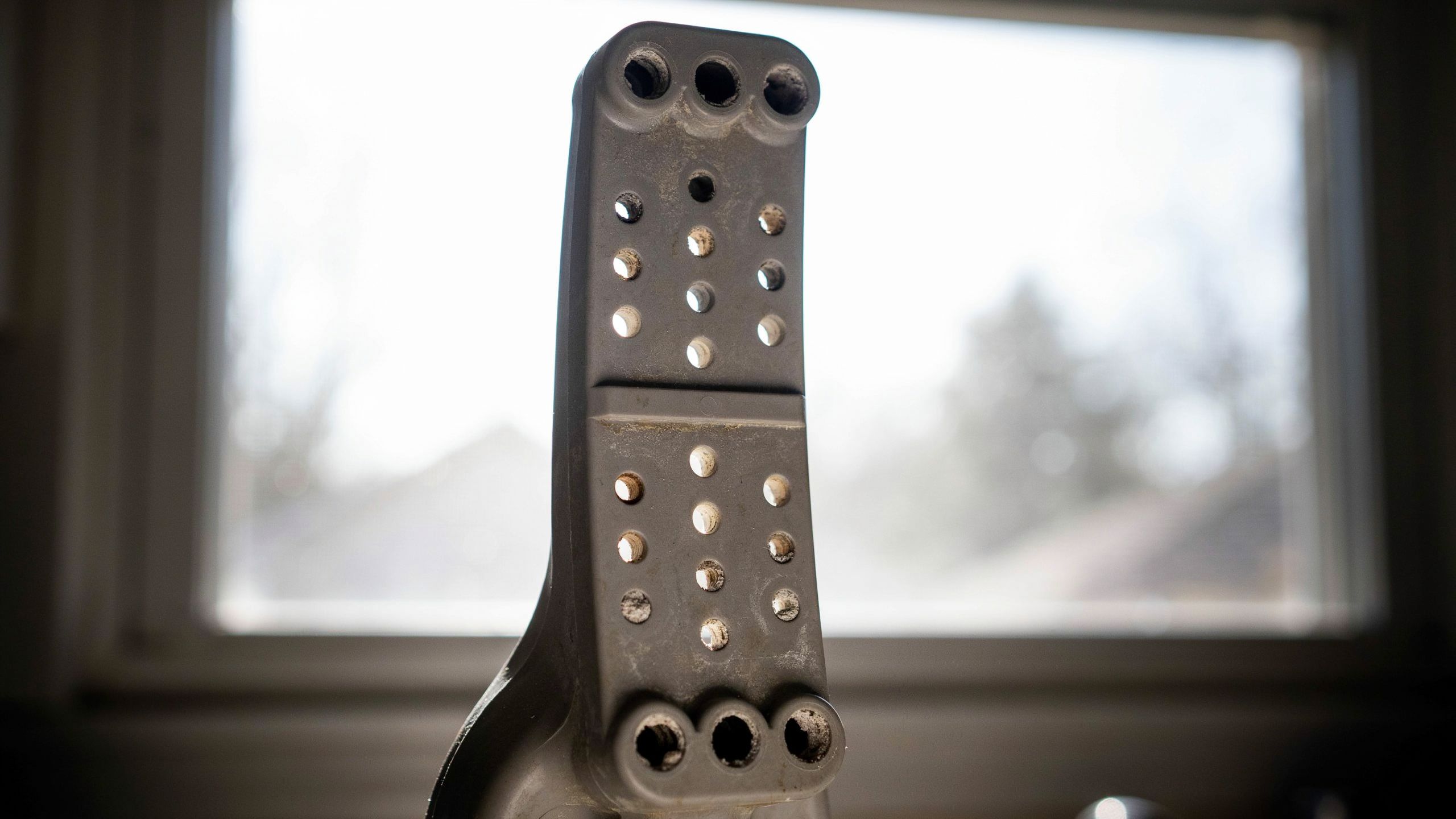 A dishwasher spray arm removed from the machine with debris lodged in several small spray holes