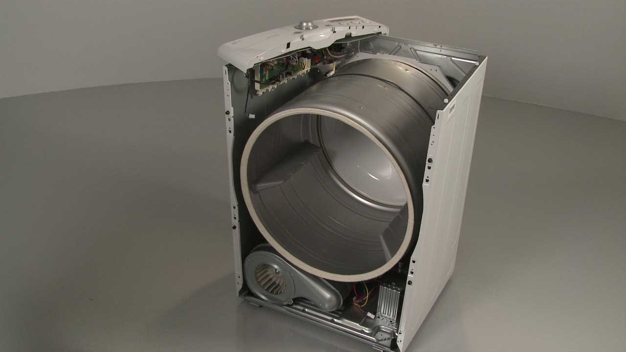 A dryer cabinet with the drum removed, exposing the base, rear support rollers, and lint buildup areas