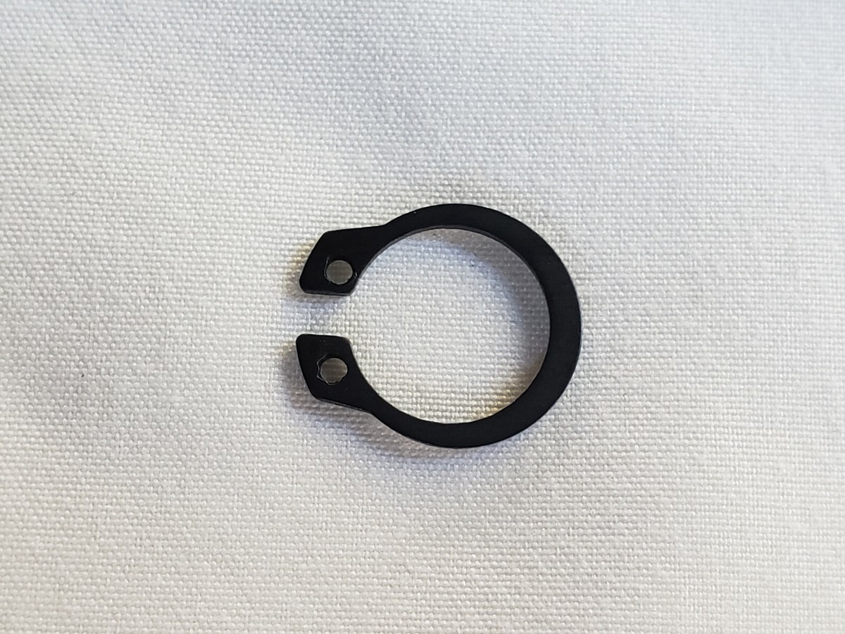 A dryer drum roller on its shaft with a retaining clip being removed using needle-nose pliers