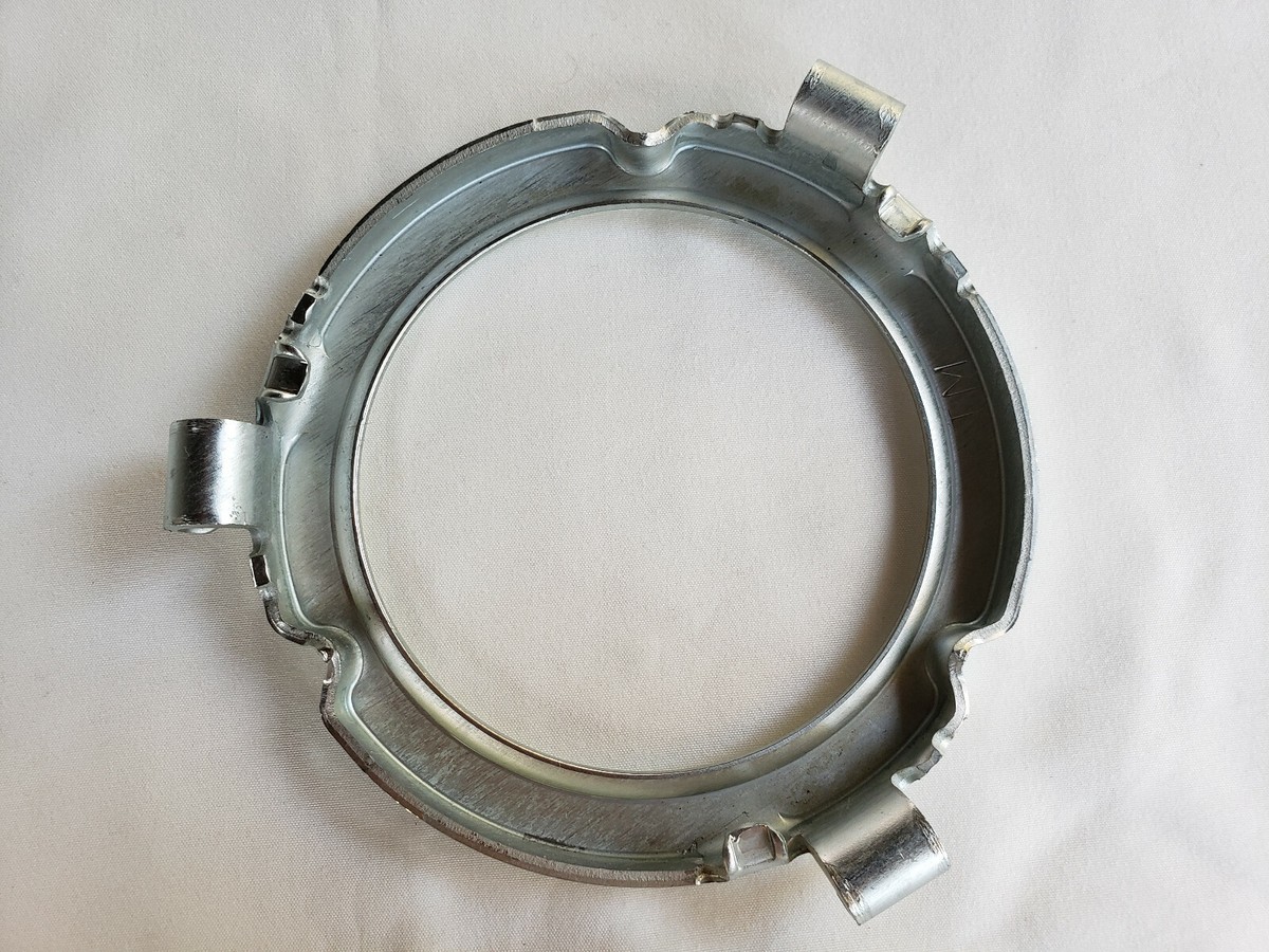 A garbage disposal mounting ring and sink flange assembly viewed from inside an under-sink cabinet, showing the flange, mounting screws, and locking ring