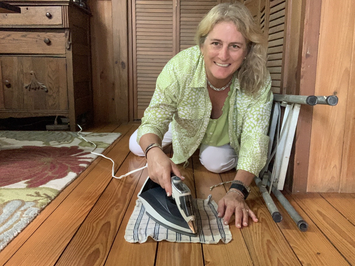 A household iron held over a damp cloth placed on a dent in a hardwood floor