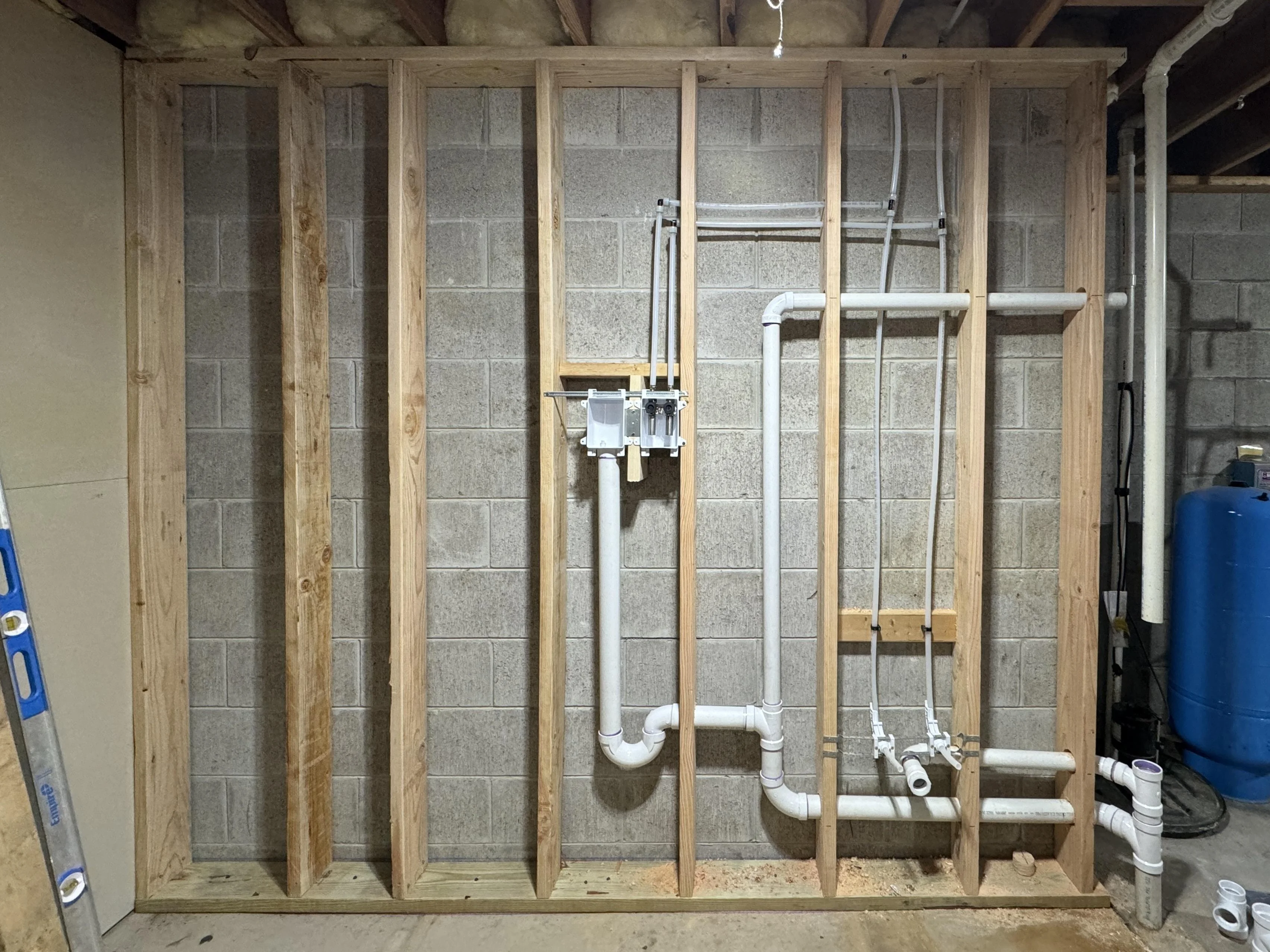 A laundry room standpipe drain box with a washing machine drain hose inserted, showing the drain opening where a clog could cause backup