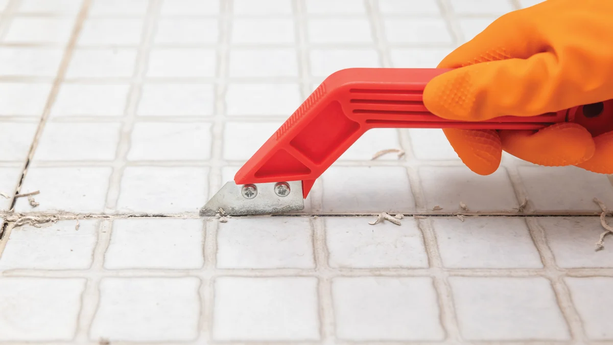 A manual grout saw removing grout around a single tile