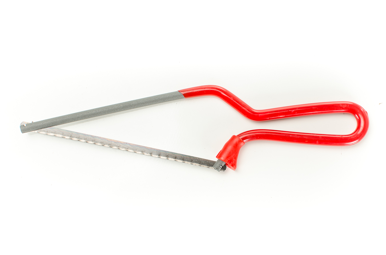 A mini hacksaw cutting through a small plastic pipe section under a sink in a tight space