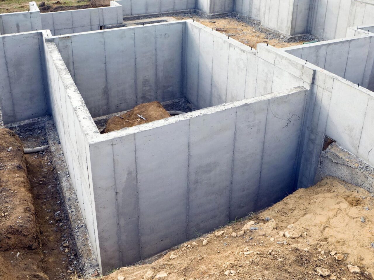 A poured concrete basement wall with a thin vertical crack beneath a basement window