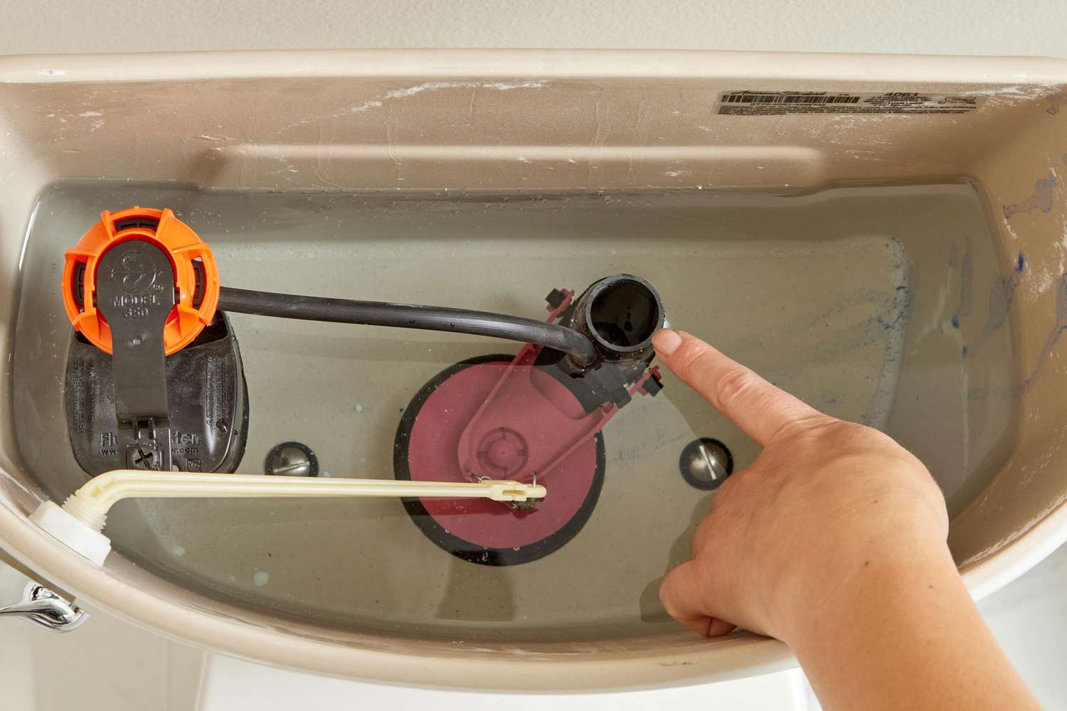 A real photo of a toilet tank with a few drops of blue food coloring spreading in the tank water