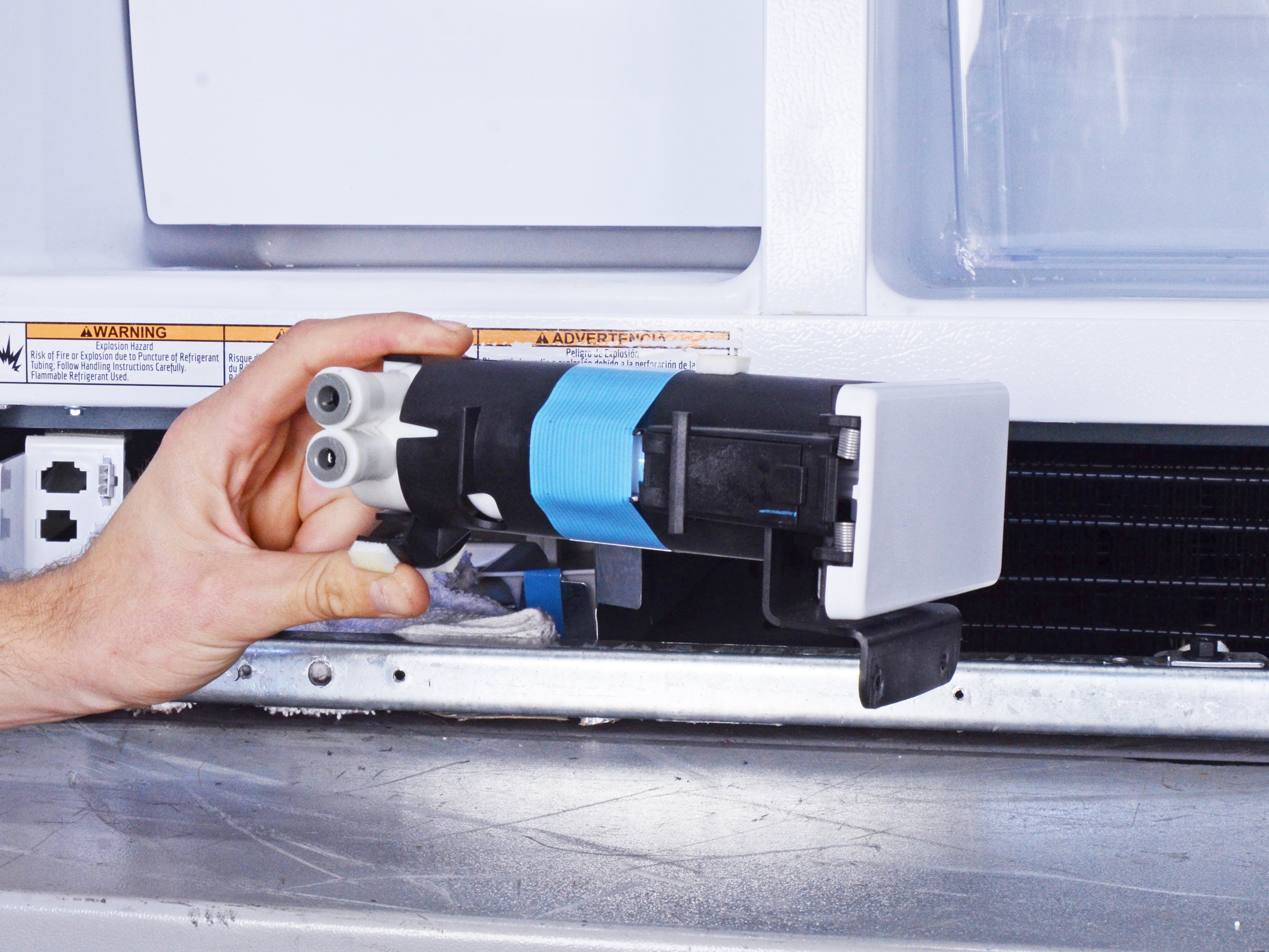 A refrigerator interior with the water filter compartment open, showing moisture around the filter housing area