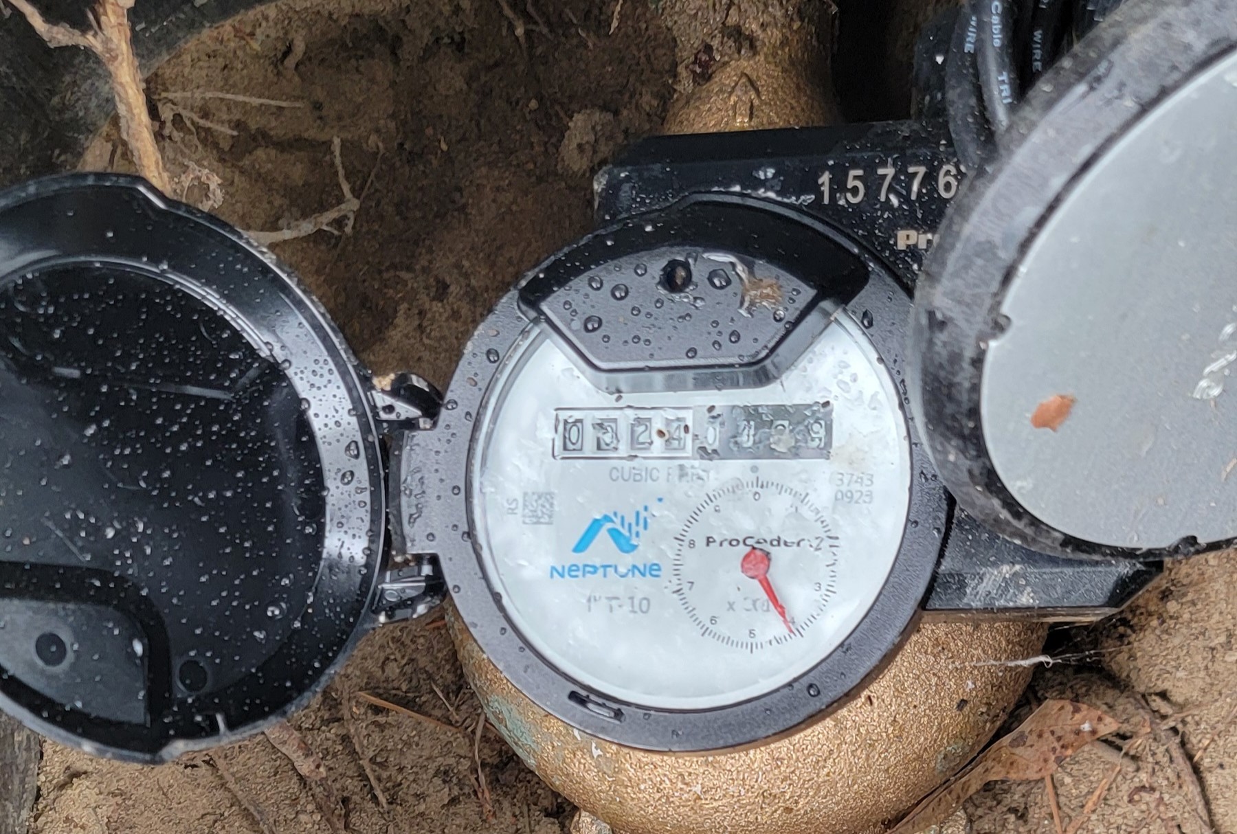A residential water meter with the small leak indicator dial visible, photographed up close