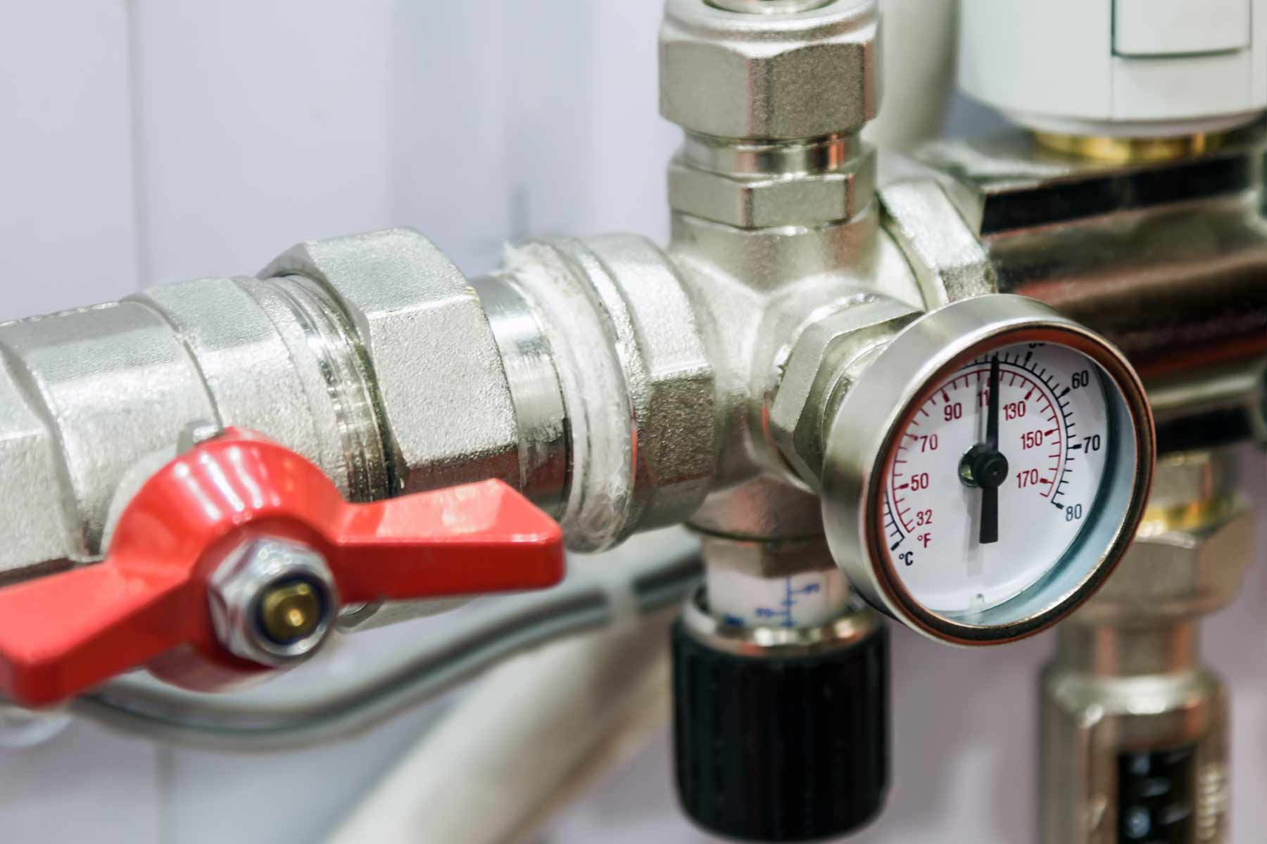 A residential water pressure reducing valve installed on the main water line near the foundation wall