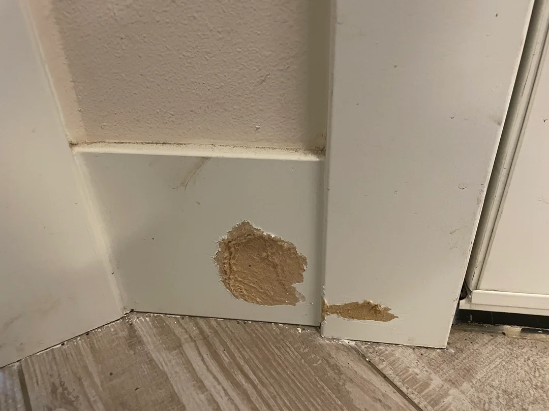 A sanding sponge smoothing the bottom edge of a painted MDF baseboard