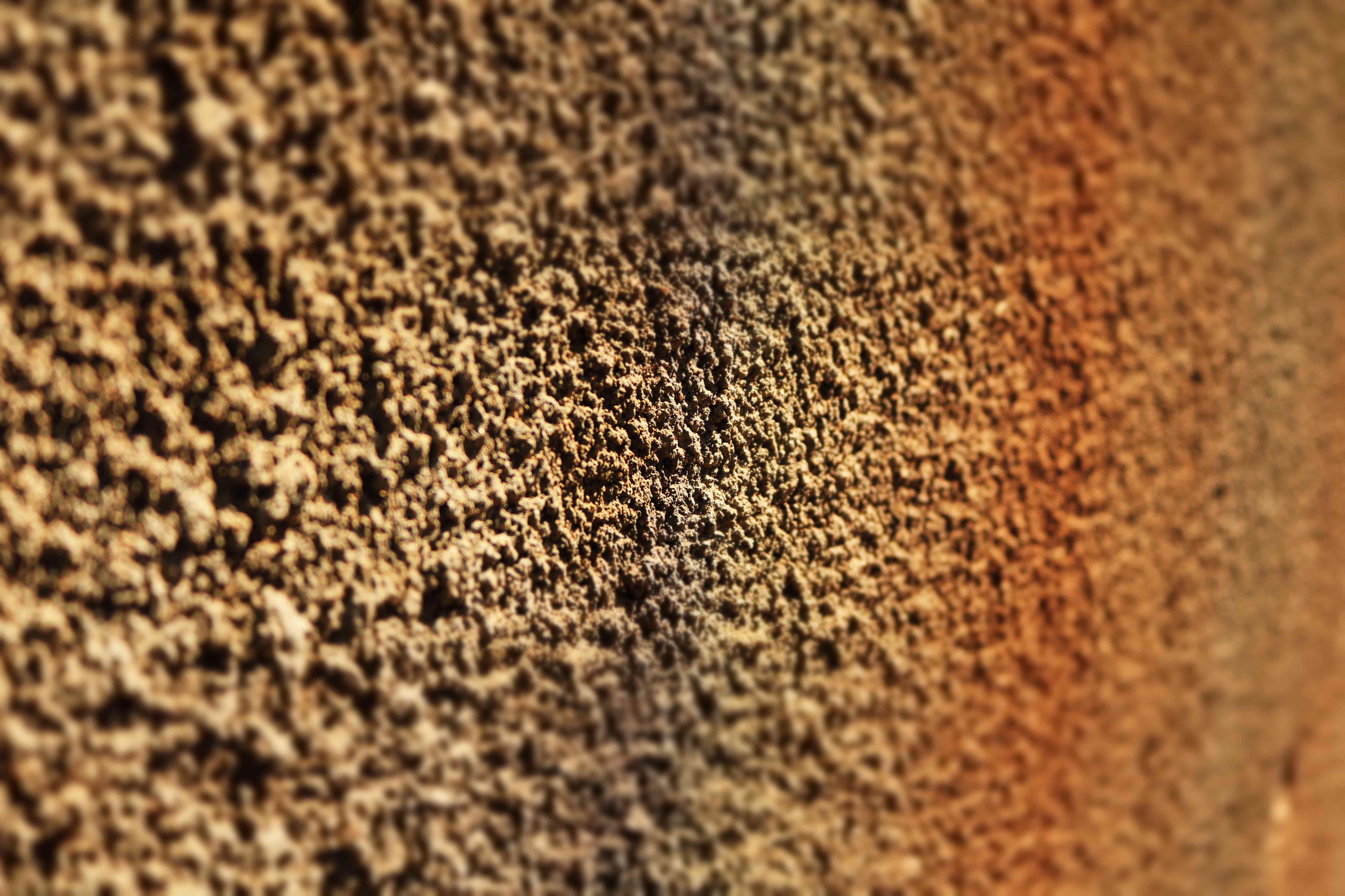 A spray texture can being used on a wall patch area, with fine orange peel texture forming on the surface