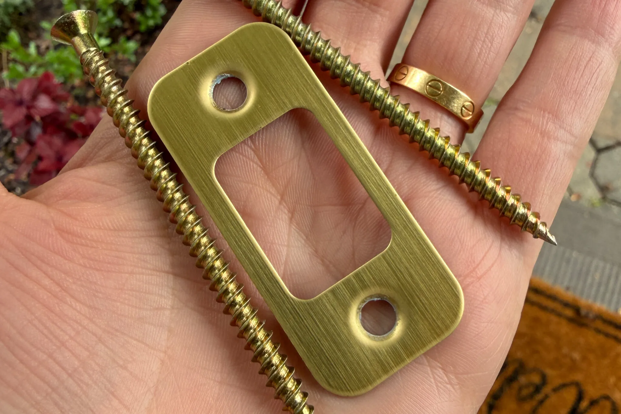 A strike plate being installed on a wooden jamb with long screws aligned to be driven into the framing