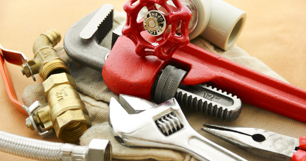 An adjustable wrench tightened onto a brass shutoff valve hex nut under a sink