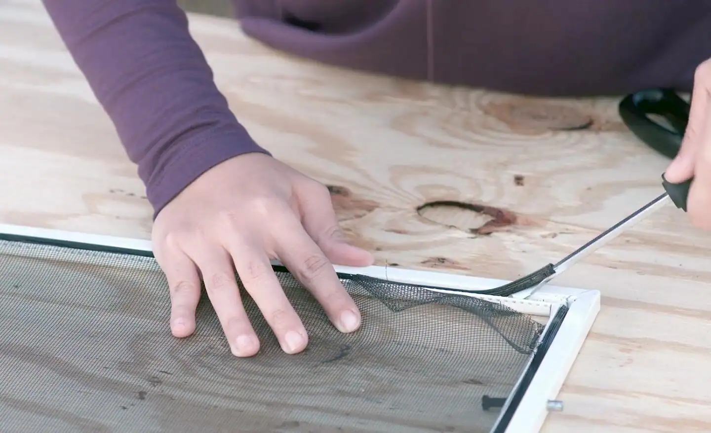An aluminum window screen frame corner showing the plastic corner connector and the spline groove