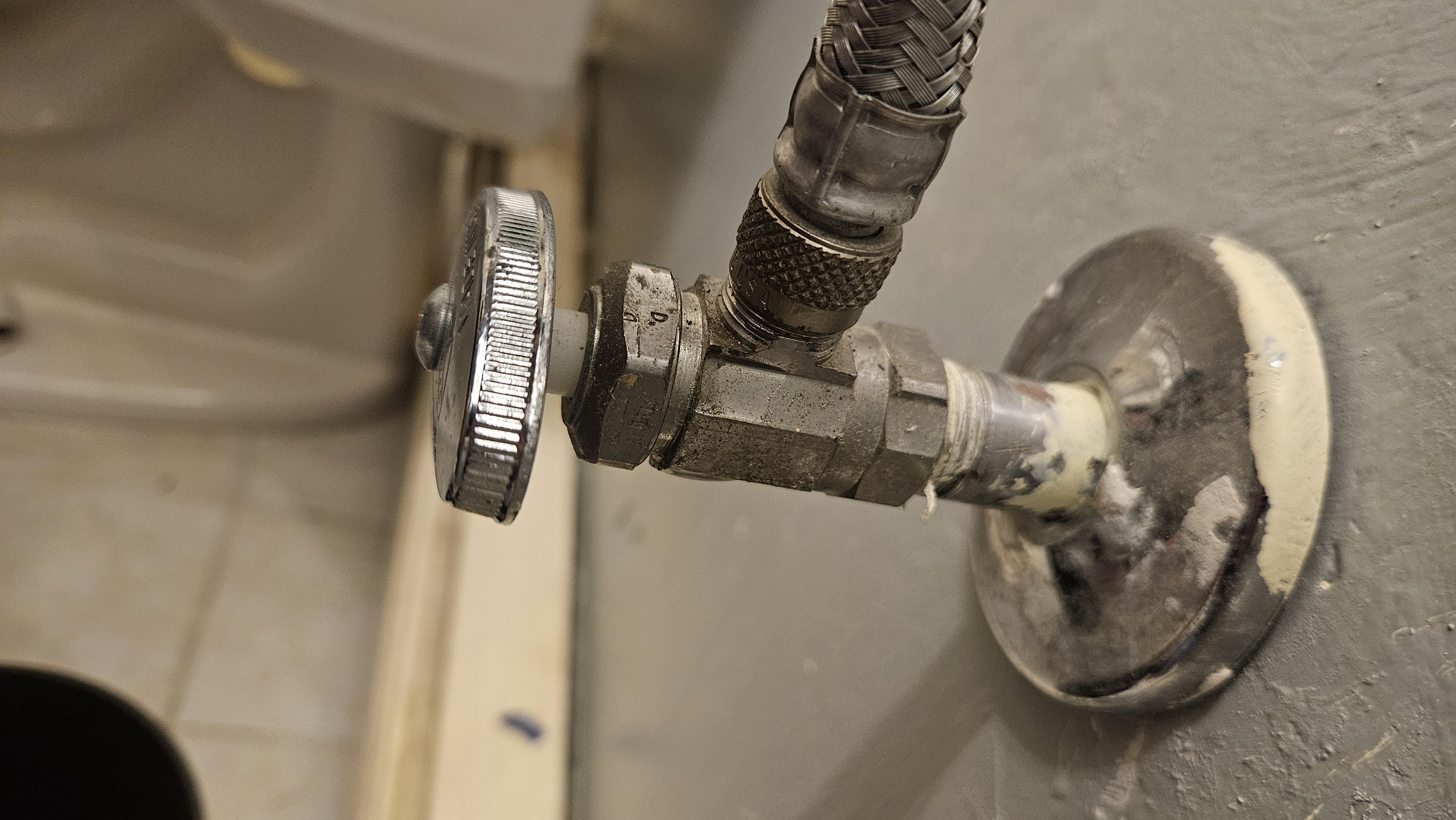 An under-sink angle stop valve connected to a braided stainless supply line, shown in an open position