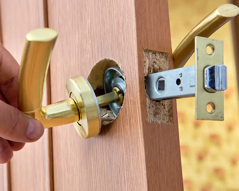 Close-up of a door latch bolt extended from the edge of a wooden door, showing the beveled face and spring mechanism