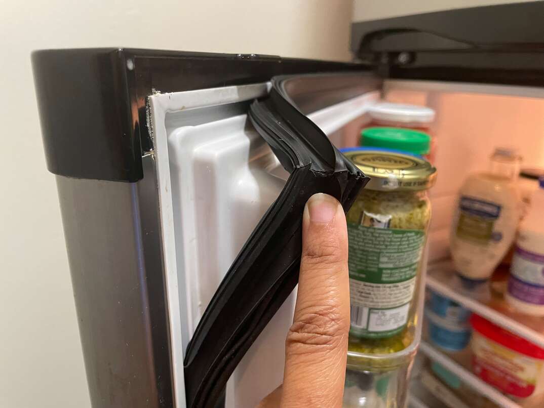 Close-up of a refrigerator door gasket showing a slightly deformed section along the door seal