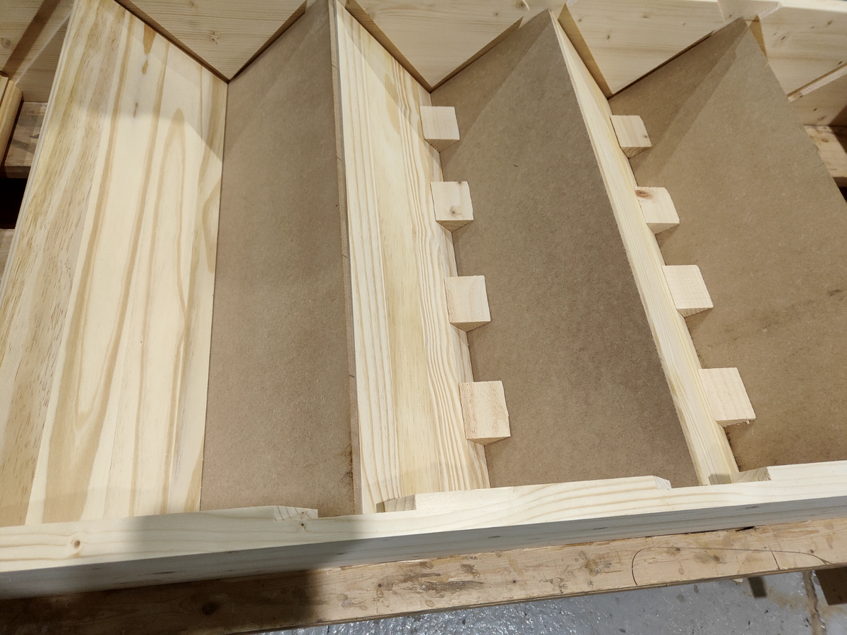From under a staircase, wooden glue blocks installed at the joint between a stair tread and riser with screws driven into the blocks