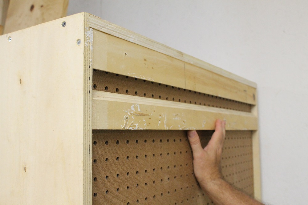 Interior of a cabinet showing narrow wooden cleats screwed to both side walls, forming a ledge that supports a shelf