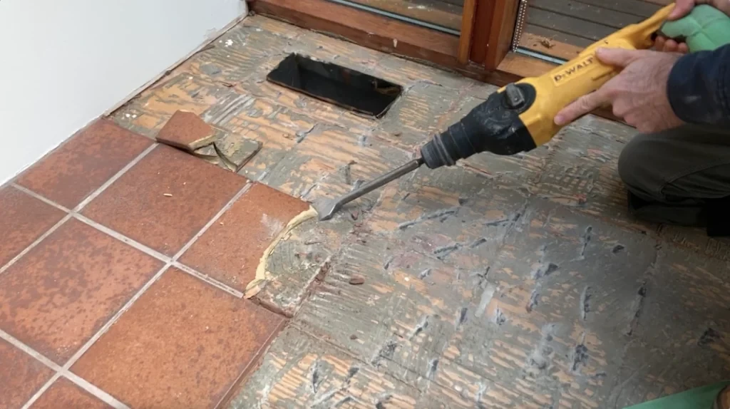 Old thinset being scraped from a tile cavity with a stiff putty knife to create a flat setting surface
